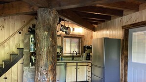 A rustic kitchen with wooden walls, a stone pillar, a stainless steel refrigerator, and a stone-tiled floor. - Boo Bear: New luxe lakeside cabin, hottub, caves, fast Wifi @ BearTrackLake (Beattyville)