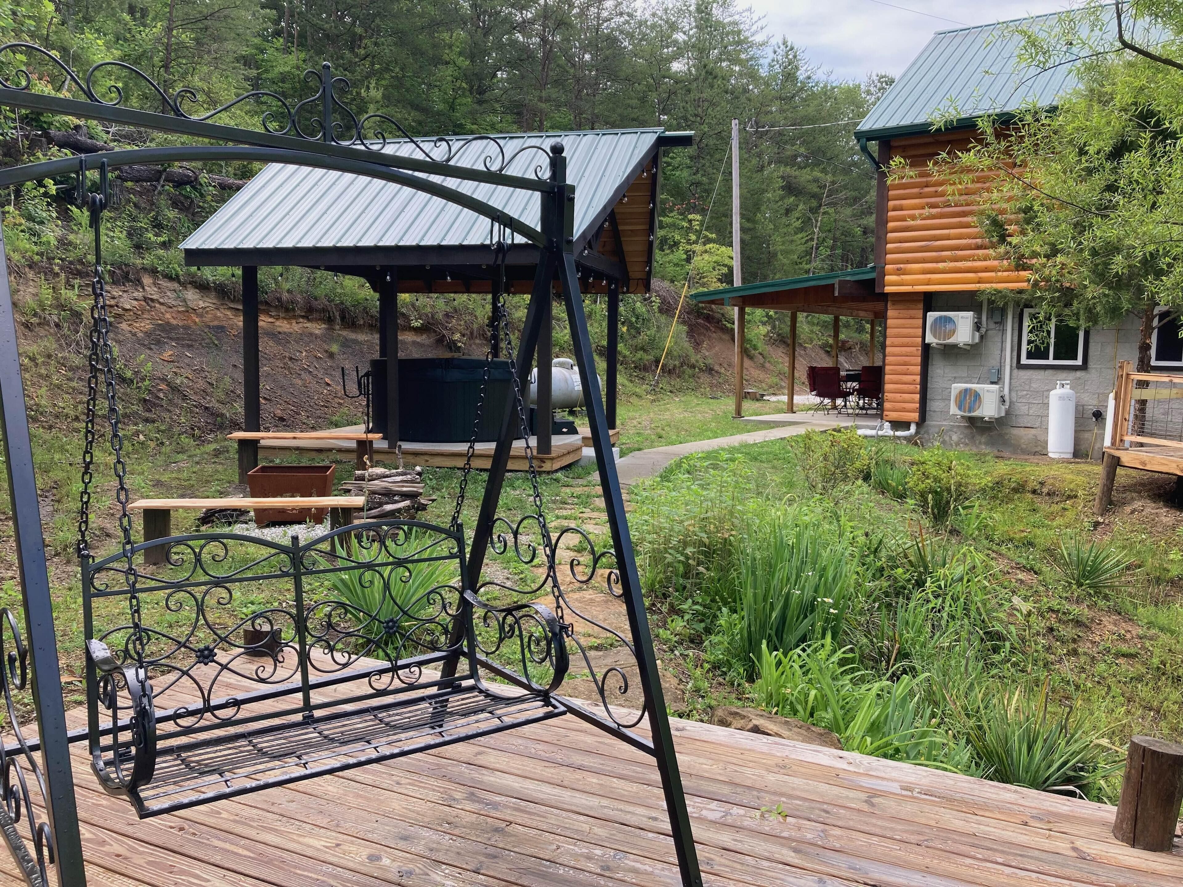 Una terraza de madera con un columpio y una zona de estar cubierta.