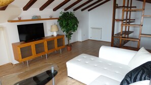 Relax in this open living space with a flat-screen TV, comfortable sofa, and a potted plant.