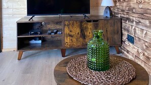 A wooden interior with a mounted TV, a small table with a decorative vase, and a poster on the wall. - Bogs des Bauges Chalet L'arcalod (Arith)