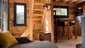 A cozy cabin interior with a sofa, a small table, a TV, and a kitchen area. - Bogs des Bauges Chalet L'arcalod (Arith)