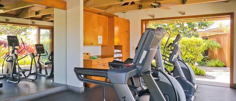 Une salle de sport équipée de tapis de course, de vélos d’exercice et dotée d’un plafond en bois.