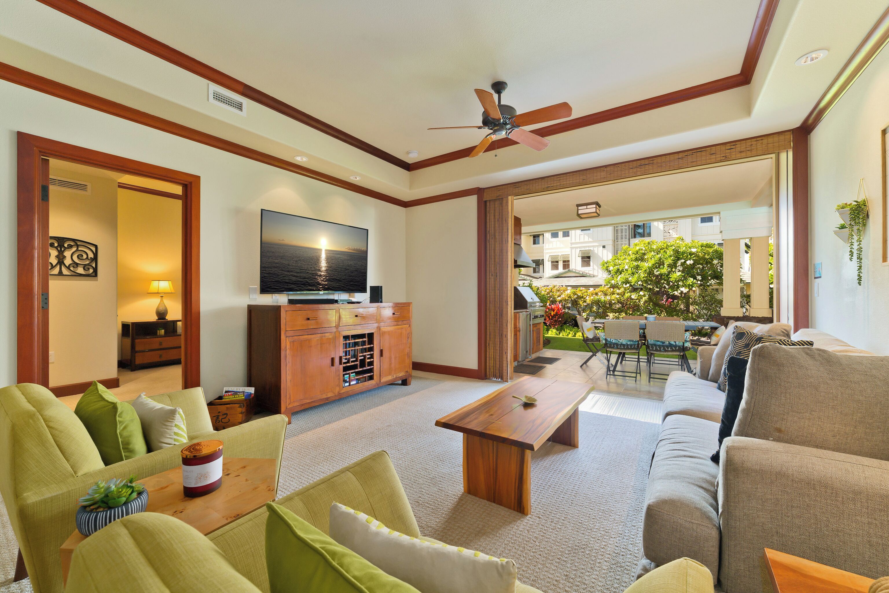 A spacious living room with a flat-screen TV, wooden coffee table, and comfortable seating.