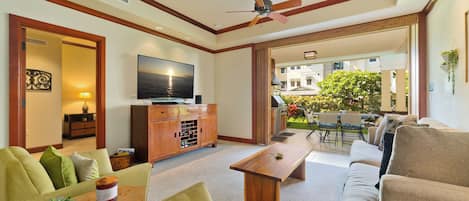 A spacious living room with a flat-screen TV, wooden coffee table, and comfortable seating.