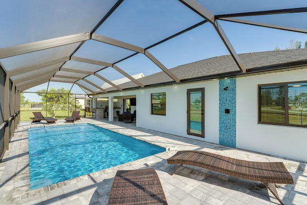 Un área de piscina techada con sillones de descanso y una terraza.