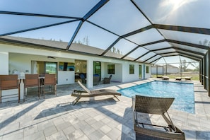 Zona de piscina exterior cubierta con sillas de descanso, un bar y un patio con vistas a la piscina.