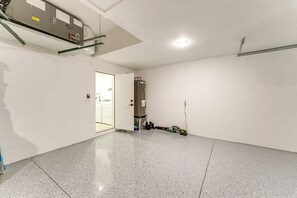 Una habitación amplia y bien iluminada con piso pulido, una puerta que da a otra zona y un cuadro eléctrico visible en el techo.