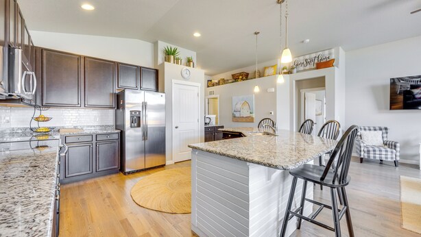 A modern kitchen with granite countertops, stainless steel appliances, and a central island with bar stools. - Stunning Peyton Retreat w/ Game Room, Private Yard (Peyton)