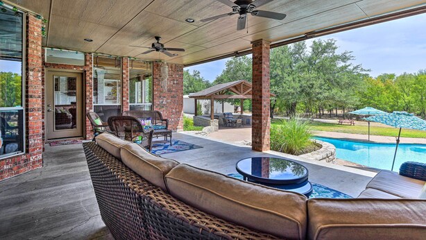 A covered patio with wicker furniture, a pool, and a view of a house and trees. - Come see why Granbury is Texas' best kept secret! Unwind at La Paloma - Enjoy!  (Granbury)