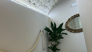 A staircase with a potted plant, a mirror, and a coiled rope on the wall. - B&B La Fabbrica di San Pietro (Vasto)