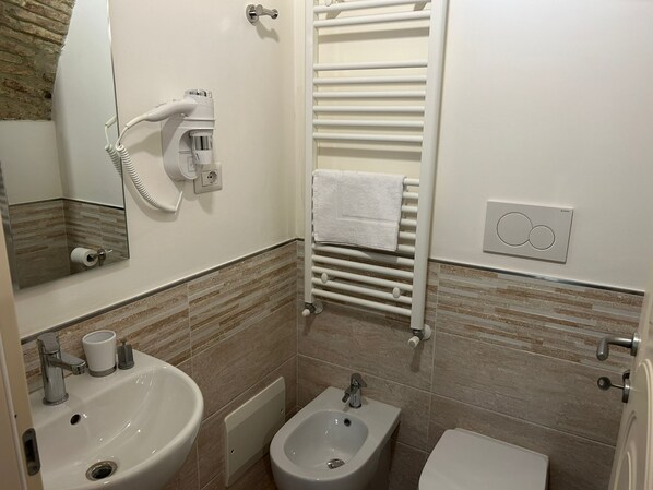 Un baño con lavamanos, bidé, inodoro, toallero y espejo.
