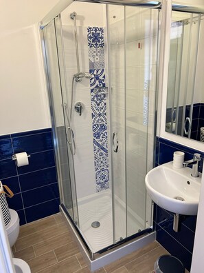 A bathroom with a glass shower enclosure, a white sink, and blue patterned tiles. - B&B La Fabbrica di San Pietro (Vasto)