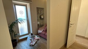 A spacious living area with a modern design, featuring a large window, a sofa, a coffee table, and a potted plant. - B&B La Fabbrica di San Pietro (Vasto)