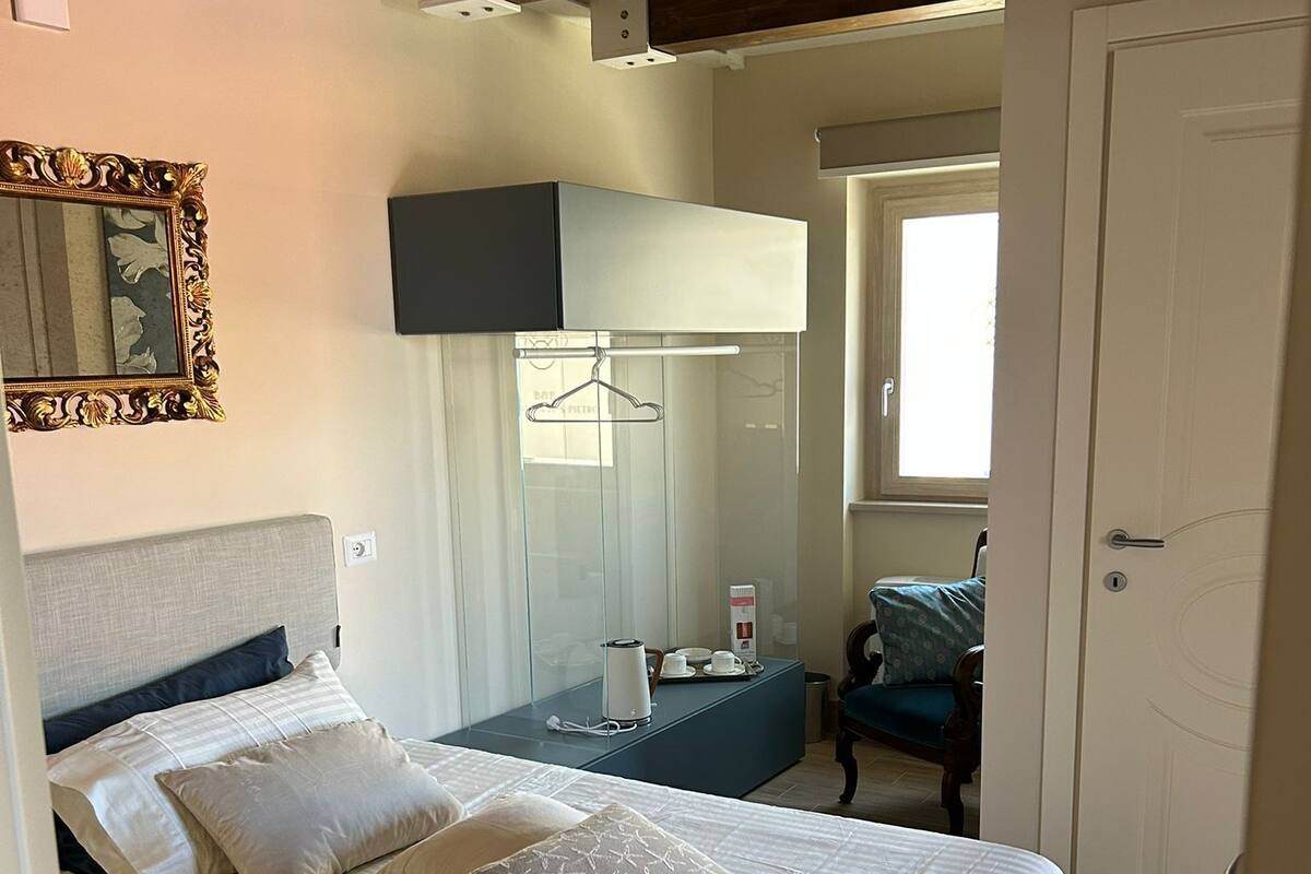 A bedroom with a bed, bedside table, mirror, and wardrobe.