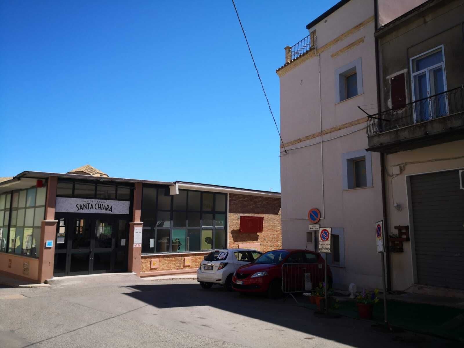 Ein Gebäude mit einem Schild, auf dem 'SANTA CHIARA' steht, und einem Parkplatz mit Autos.