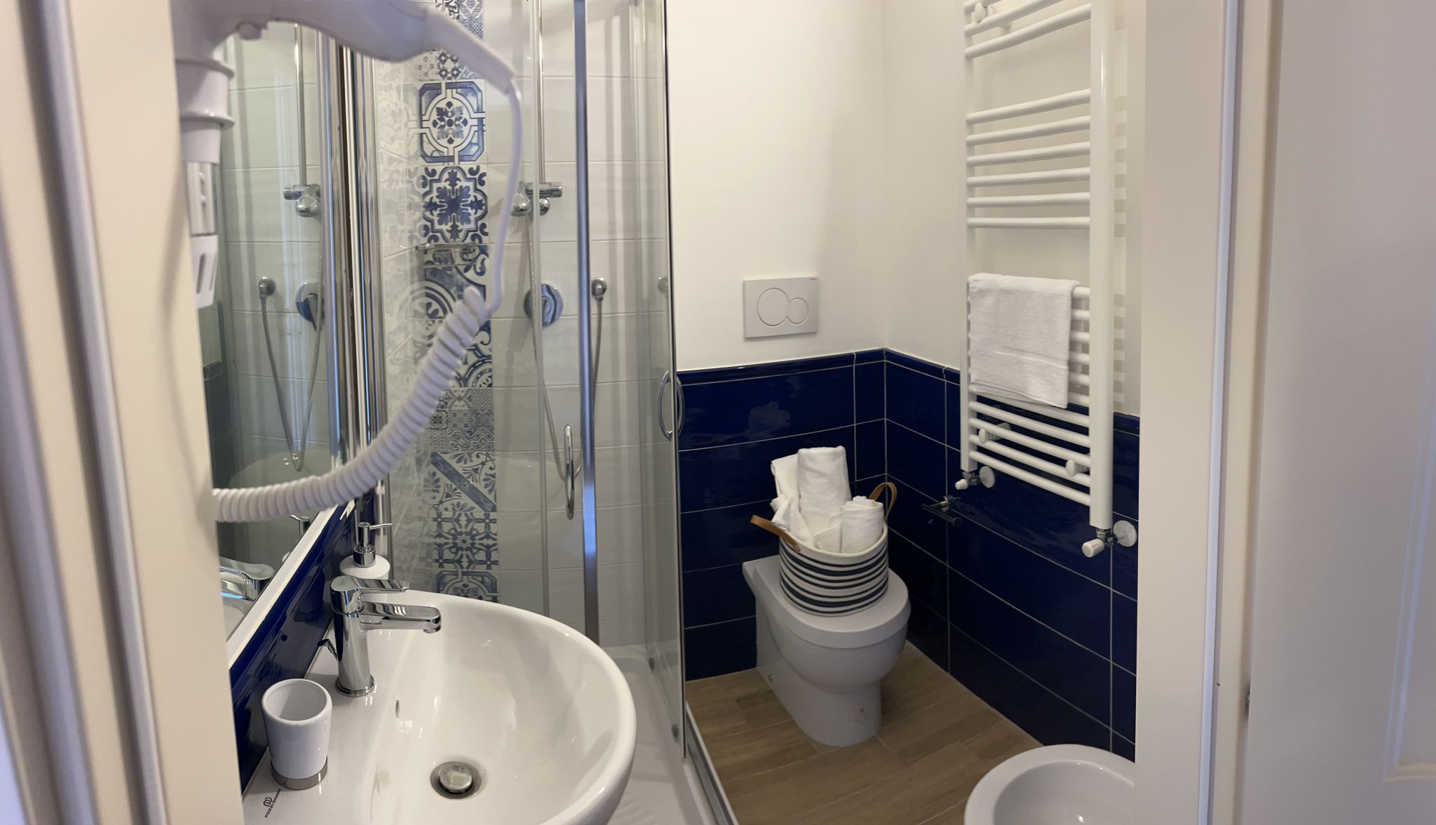 A bathroom with a glass-enclosed shower, a sink, a toilet, and a towel rack.
