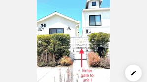 A pathway leading to a building with a white facade and a red arrow pointing to an entrance gate. - Stylish Studio Center of North Park  (San Diego)