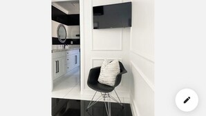 A modern kitchen with white cabinets, a black countertop, and a black chair with a white cushion. - Stylish Studio Center of North Park  (San Diego)