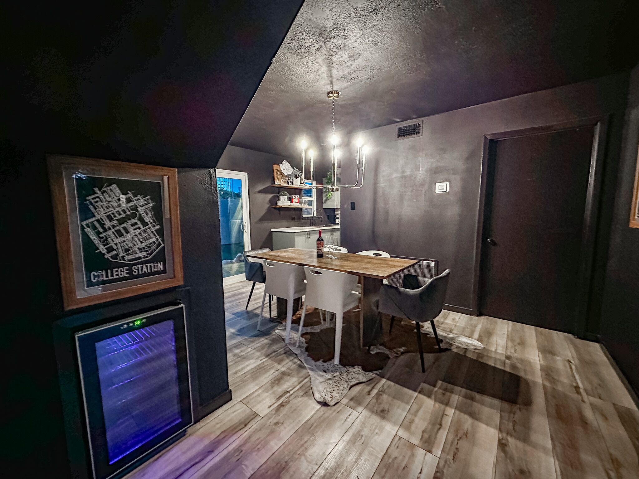 A modern kitchen with a wooden table and chairs, a built-in oven, and a map on the wall.
