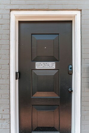 A dark brown door with a sign reading "North Central Loft" above a recessed entrance.