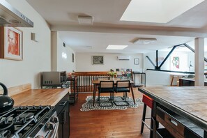 A modern kitchen with a gas stove, microwave, and a dining area with a wooden table and chairs.