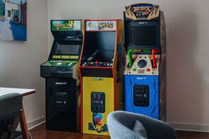 Three arcade machines in a room with a wooden floor and a white wall.