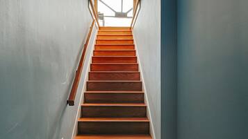 A staircase with wooden steps and a metal handrail, leading to an open area with natural light.