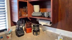 A kitchen with a wooden cabinet containing dishes, glasses, and a blender. - Something to Write Home About @ The Wild West 40  (Cane Beds)