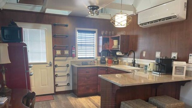 A kitchen with a central island, wooden cabinets, and a dining area with a table and chairs. - Something to Write Home About @ The Wild West 40  (Cane Beds)