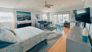 Un dormitorio moderno con una cama grande, ventilador de techo y televisión.