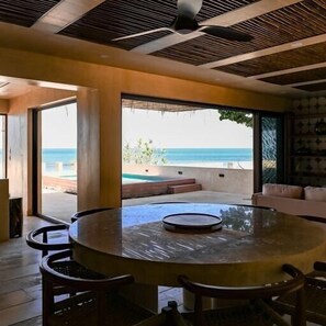 Een moderne eetruimte met een ronde tafel en stoelen, grote ramen met uitzicht op de oceaan.