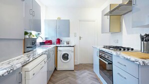 Une cuisine compacte équipée d’un lave-linge, d’une cuisinière et d’un four à micro-ondes.
