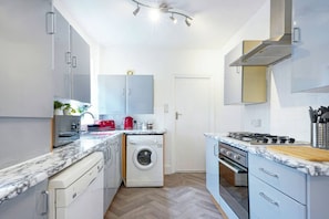 A compact kitchen with a washing machine, a stove, and a sink. - City Centre House • Sleeps 7 • Free Parking • Fast Wifi • Sky TV • Netflix • Self-Check-In • Yoko Property (Northampton)