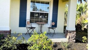 Une maison avec une véranda, deux chaises et une table.