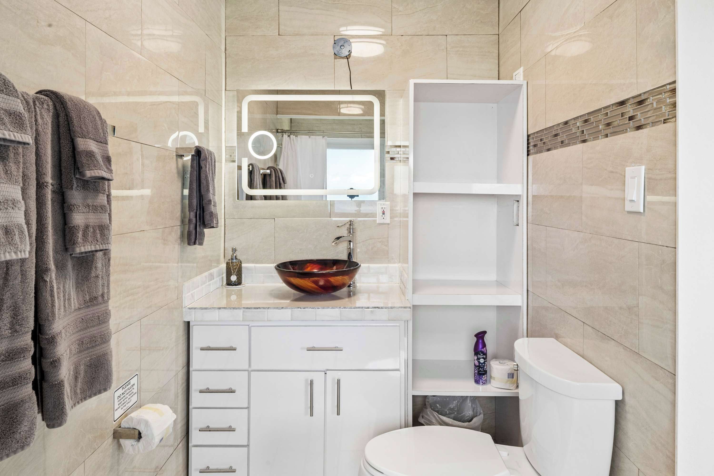 Un baño con un inodoro blanco, un lavabo, un espejo y toallas colgadas en la pared.