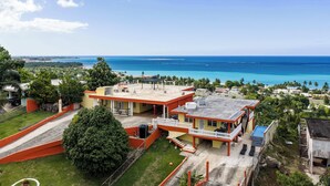 A coastal property with a large house, a swimming pool, and a view of the ocean.