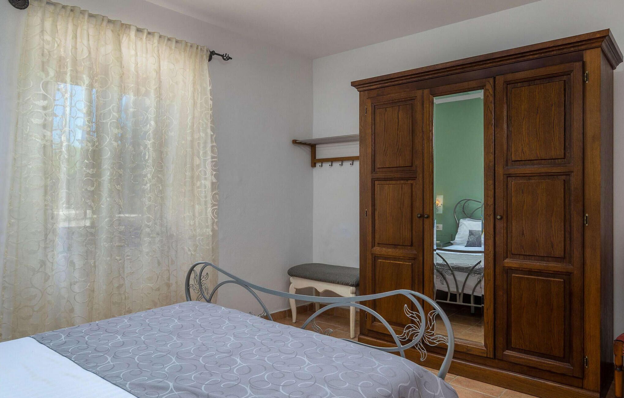 A bedroom with a bed, a wardrobe, a bench, and a mirror.