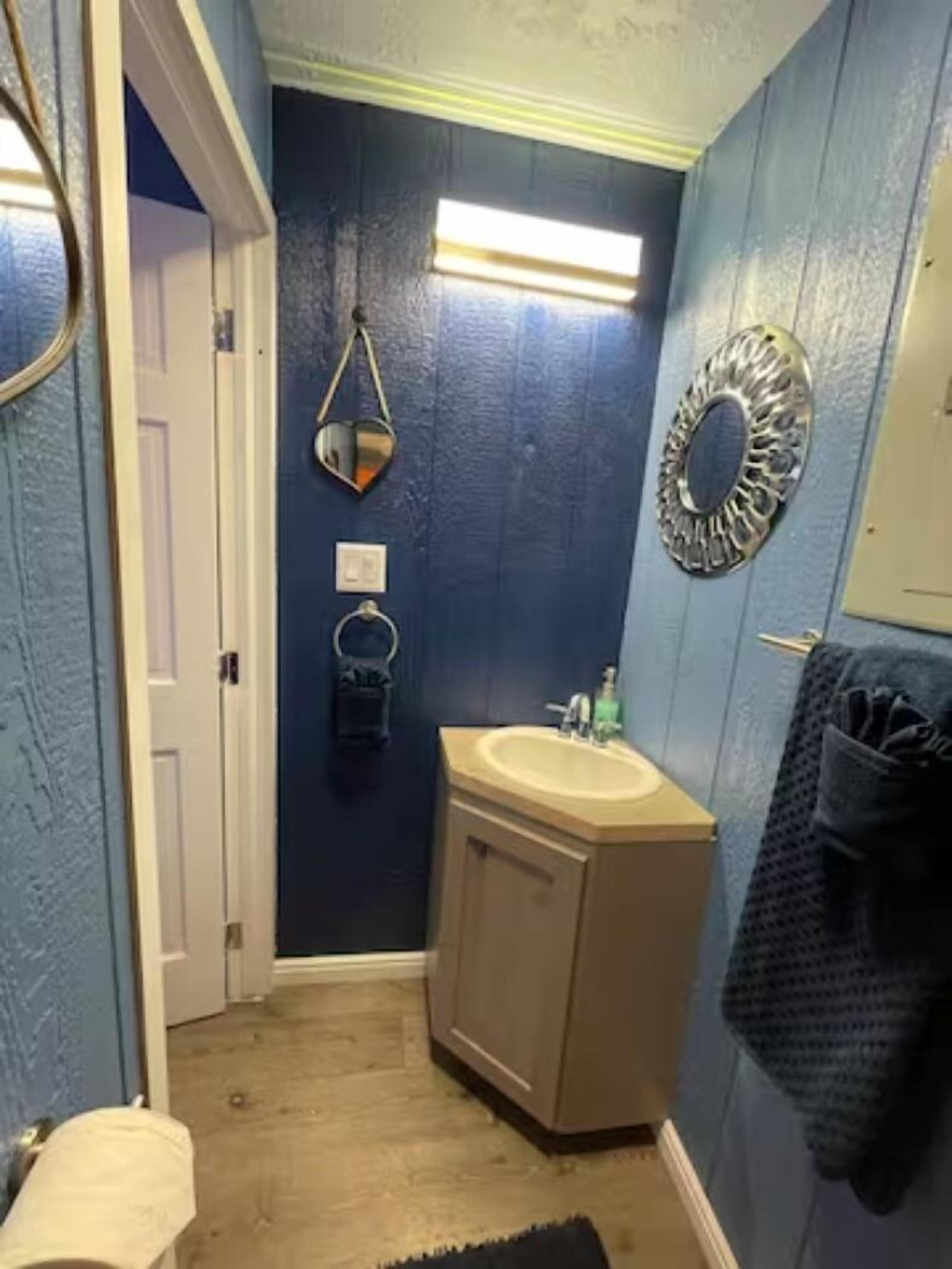 Un baño con lavabo, espejo y toallero.