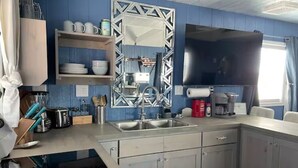 Una cocina moderna con un lavamanos integrado, electrodomésticos de acero inoxidable y un televisor de pantalla plana grande.
