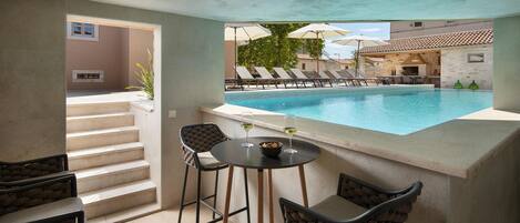 A poolside area with a bar, chairs, and a view of the pool.