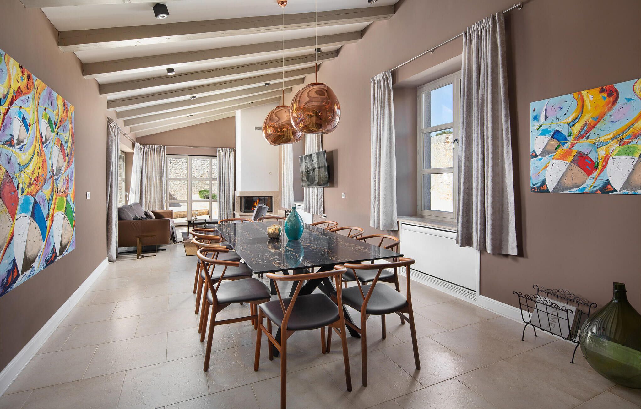 A spacious dining area with a long table, multiple chairs, and pendant lighting.