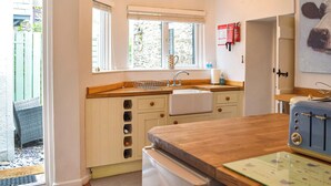 A compact kitchen with a wooden countertop, a sink, and a small refrigerator. - 2 bedroom accommodation in Cwrt-newydd (Cwrt-newydd)