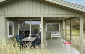 A covered outdoor seating area with a table and chairs, a swing, and a view of the surrounding landscape.