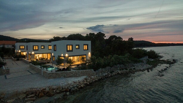 Ein modernes, zweistöckiges Haus mit Swimmingpool in der Nähe von Gewässer.
