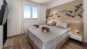 Ein Schlafzimmer mit Bett, Fernseher, einem Fenster mit Aussicht und einer Wanddekoration.