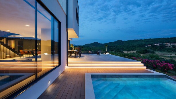 Ein modernes Haus mit Pool, Sitzgelegenheiten im Freien und Blick auf die Landschaft.