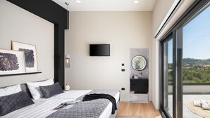Ein modernes Schlafzimmer mit zwei Betten, einem Fernseher, einem Badezimmer mit Spiegel und einem Balkon mit Blick.
