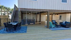 An outdoor patio area with a pool, wooden deck, seating arrangements, and a bar area.