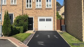 Um edifício residencial de dois andares com garagem, fachada de tijolos e gramado bem cuidado.