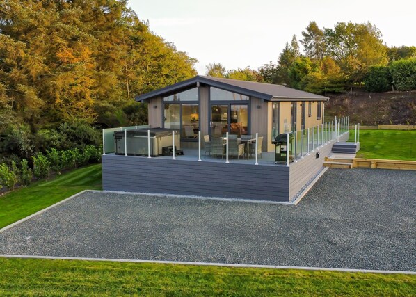 Une terrasse extérieure moderne, dotée d’un barbecue et d’un espace salon, entourée d’une végétation luxuriante et d’arbres.